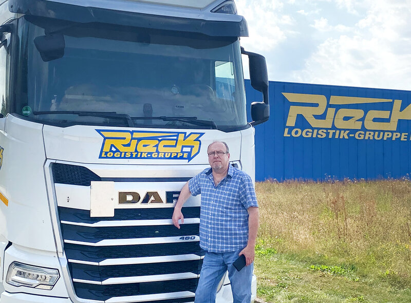 Andreas Wolff steht vor einem Kuhltransporter. Rechts ist eine Halle von Rieck zu sehen.